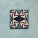 Single tile image showing the Geometry Iris 20x20cm patterned tile with a detailed geometric motif in teal, navy, terracotta-red, and cream, photographed against a soft mottled aqua background.