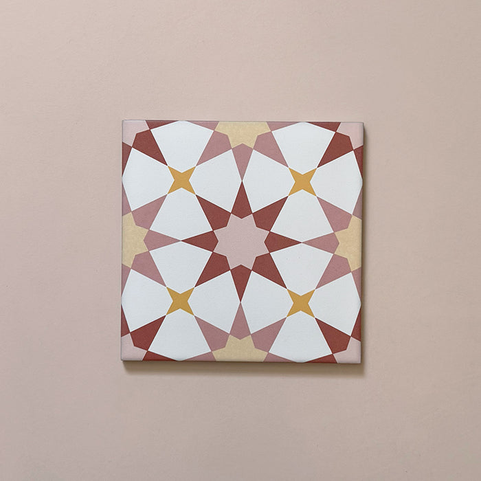 Close-up of Agraba Springs 20x20cm Moroccan-style ceramic tile featuring a geometric star pattern in terracotta, blush pink, mustard, and white tones on a soft pastel background.