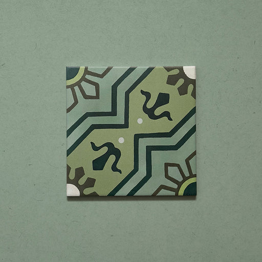 Single Brompton Verde 20x20cm Victorian-style ceramic tile featuring a geometric star and floral pattern in soft green, teal, and cream tones, shown against a matching green background in a close-up view.