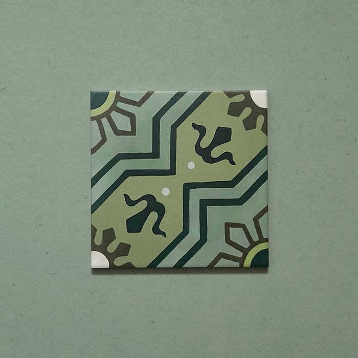 Single Brompton Verde 20x20cm Victorian-style ceramic tile featuring a geometric star and floral pattern in soft green, teal, and cream tones, shown against a matching green background in a close-up view.