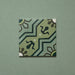 Single Brompton Verde 20x20cm Victorian-style ceramic tile featuring a geometric star and floral pattern in soft green, teal, and cream tones, shown against a matching green background in a close-up view.