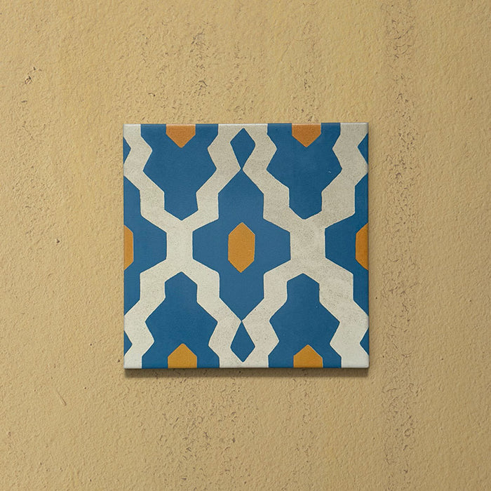 Cabana Zafini Mustard Azure 20x20cm Moroccan-style single porcelain tile with a geometric lattice pattern in deep azure blue and mustard yellow on a soft cream background with a matt finish.