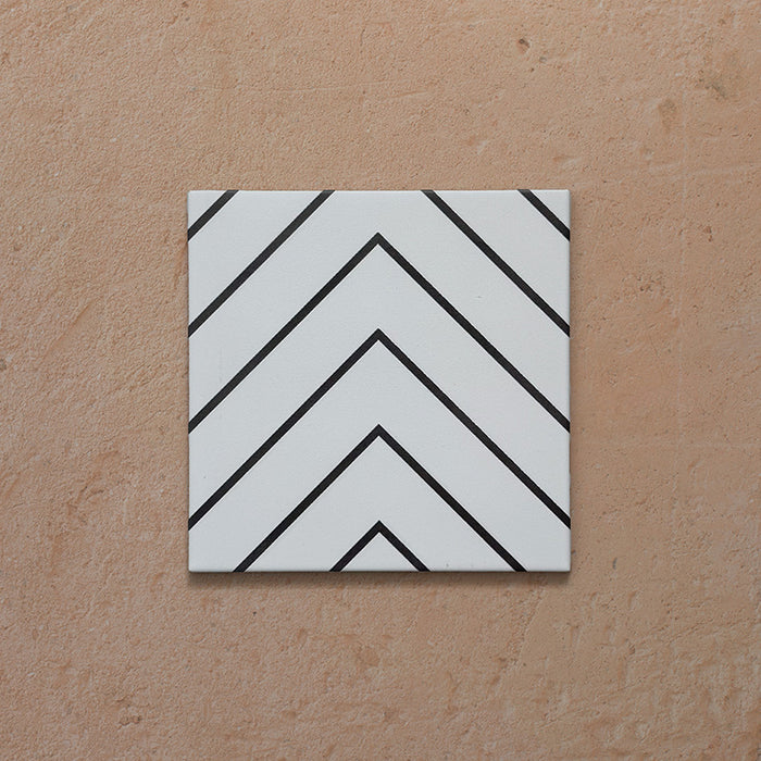 Alhambra Zig Zag Blanco 20x20cm Moroccan tile featuring a bold black chevron pattern on a white background, showcasing its modern geometric design and smooth matte finish.