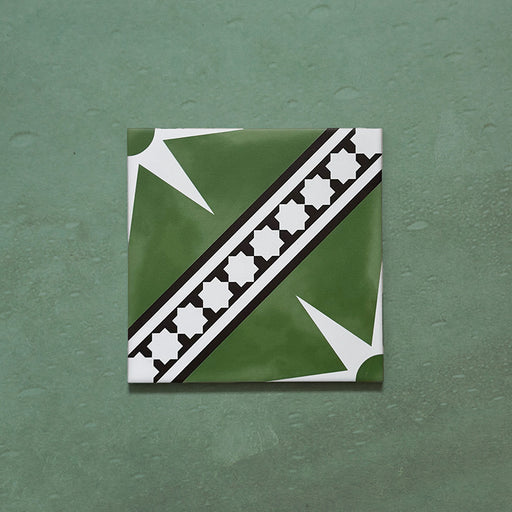 Galata Green Moroccan Style 20x20cm single tile featuring a deep green background with a bold white star motif and black geometric border pattern, displayed on a textured green surface.