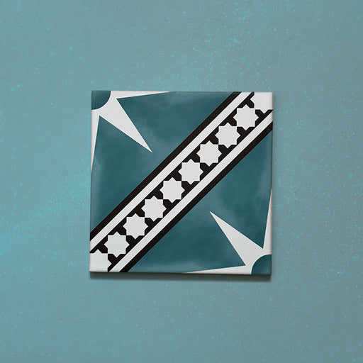 Galata Blue Moroccan Style 20x20cm single tile featuring a white star motif and black geometric border on a deep blue background, displayed against a textured teal surface.