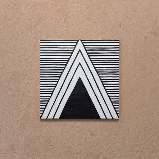Single Alhambra Pyramid 20x20cm Moroccan tile featuring a bold black and white triangular pattern with fine horizontal line detailing, displayed on a warm textured beige background.