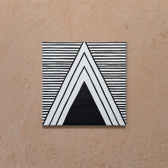 Single Alhambra Pyramid 20x20cm Moroccan tile featuring a bold black and white triangular pattern with fine horizontal line detailing, displayed on a warm textured beige background.