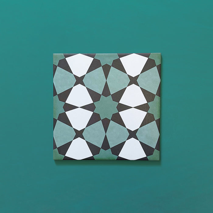Single Agraba Verde 20x20cm Moroccan-style ceramic tile with a geometric star pattern in deep green, mint, and white tones, displayed on a teal background to highlight its intricate artisan design.
