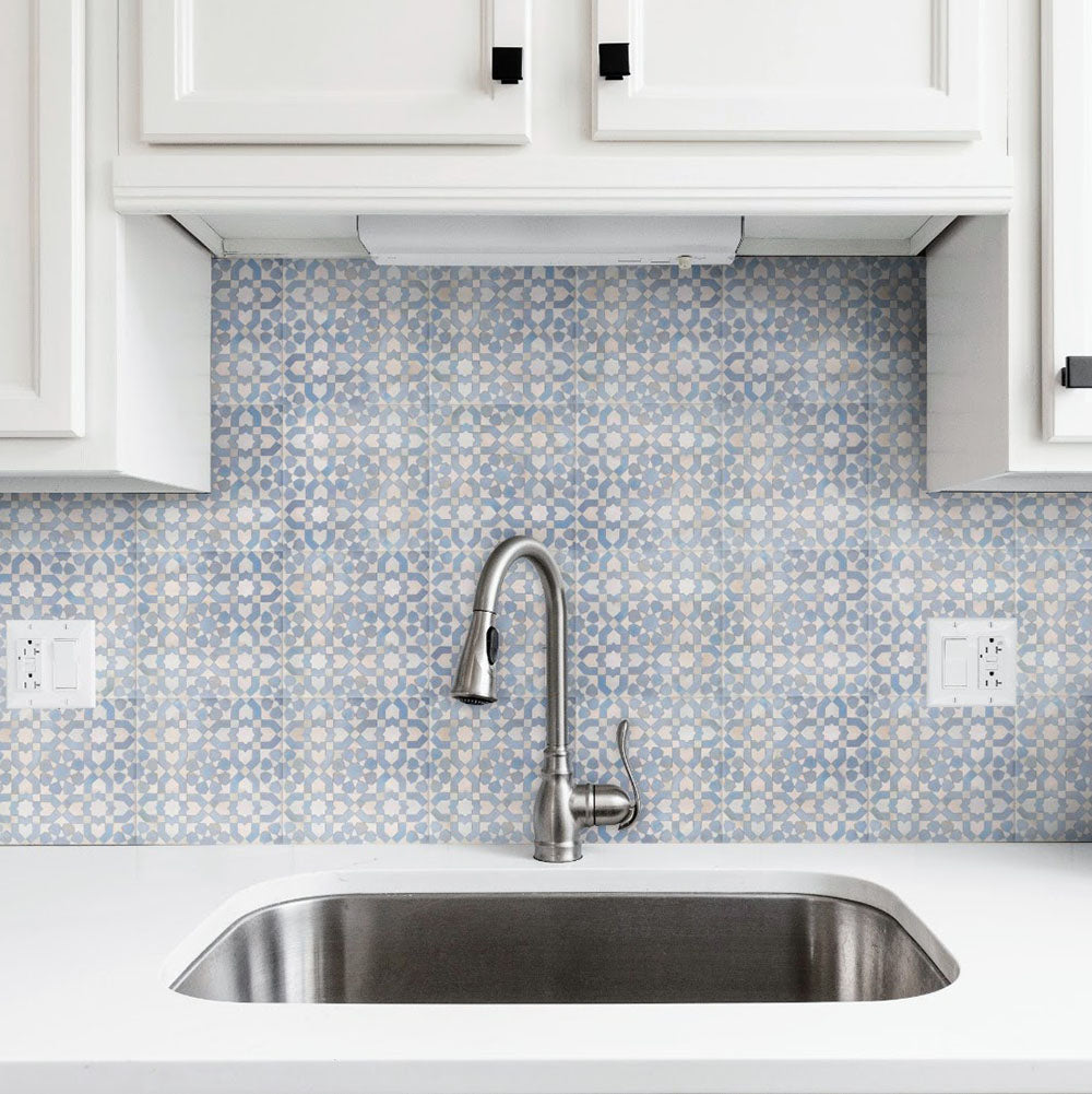 Bedouin Tetuan Blue Moroccan-style 15x15cm tiles used as a kitchen splashback, featuring a soft blue and cream geometric star pattern with white cabinetry, chrome tap, and a clean modern sink area.