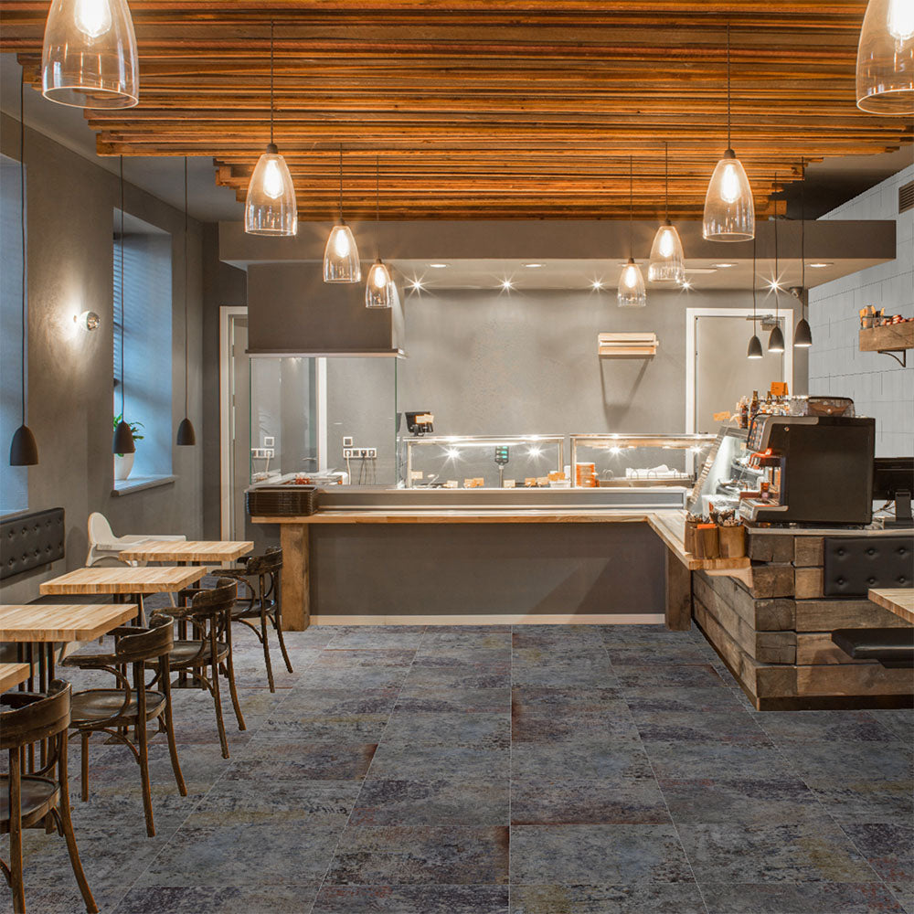 Commercial interior featuring Boheme Sinora 60 × 60cm patterned porcelain floor tiles, blending deep blue, grey and rust tones with a layered, aged-effect finish. Creates a rich, industrial-inspired look suited to contemporary spaces.