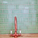 Kitchen splashback featuring Finchley Lime Green 7.5 × 15cm ceramic wall tiles with a crackle glaze finish, laid in a classic brick pattern and paired with a copper tap for a fresh, characterful design.