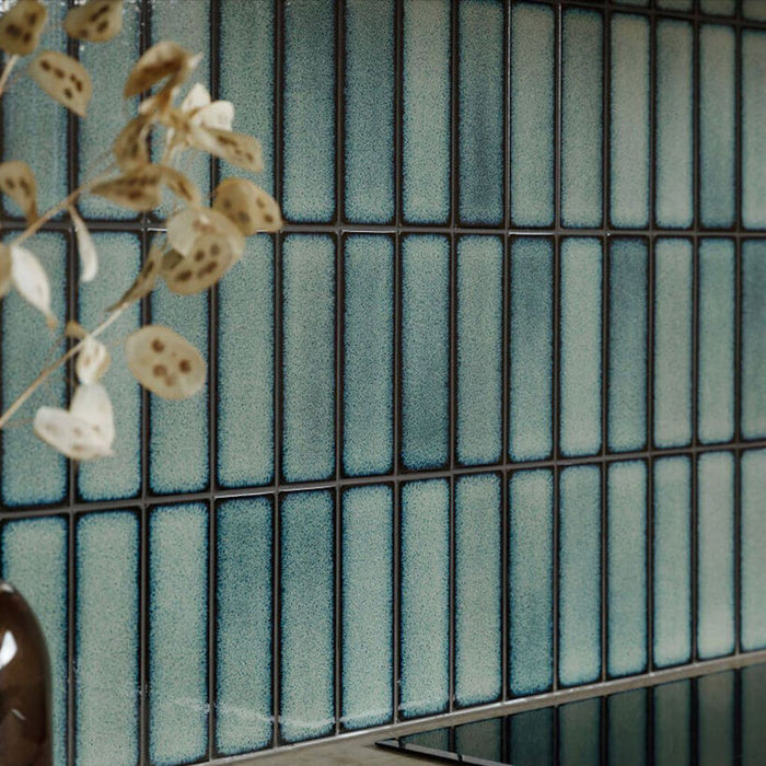 Kitchen splashback featuring Chemistry Green 6.5cm x 30cm rectangular ceramic wall tiles, installed in a vertical layout with a glossy crackle-effect green glaze and dark grout for a modern, artisan look.