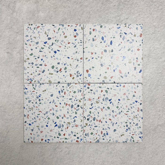 Four Confetti Tutti Frutti 25×25cm terrazzo-style porcelain tiles arranged together to show colour variation, multicoloured chips, and overall pattern effect on a white base, displayed against a light textured background.