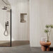 Modern bathroom featuring Storico Travertine Stone matt porcelain wall tiles with a soft travertine effect finish, paired with dark stone effect floor tiles, black shower fittings and blush pink accessories for a warm, contemporary look.