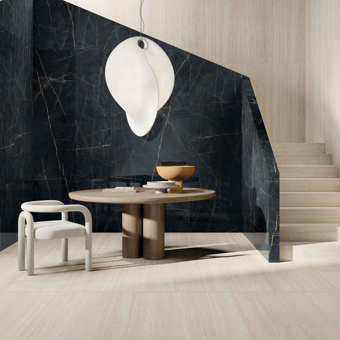 Contemporary interior featuring Storico Travertine Stone matt porcelain floor tiles with a soft travertine effect finish, paired with dramatic black marble effect stairs and feature wall to create a striking contrast in a modern living space.