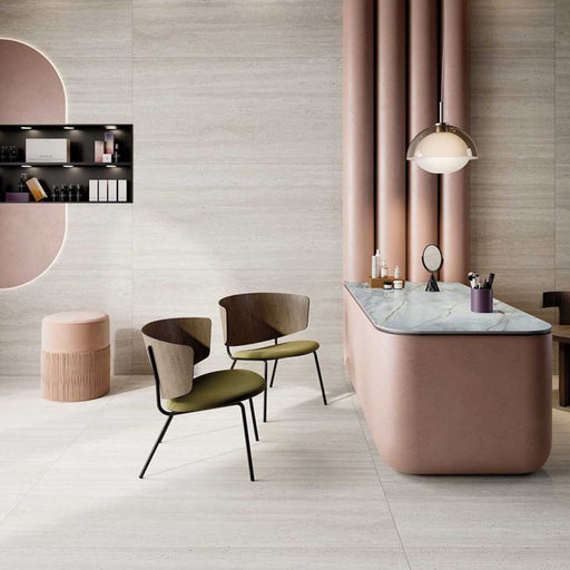 Contemporary interior featuring Storico Travertine Stone matt porcelain wall and floor tiles in a large format, paired with blush pink furnishings, marble surfaces and warm wood accents for a soft, elegant and luxurious design.