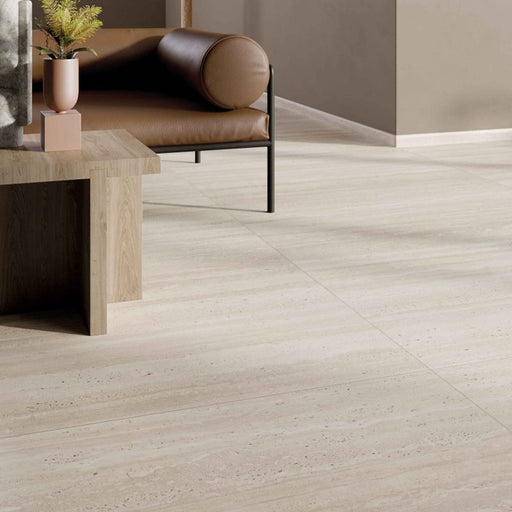 Close-up of Storico Travertine Stone matt porcelain floor tiles with a soft travertine effect finish, styled alongside warm wood furniture, leather seating and neutral décor to create a timeless, contemporary living space.