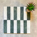 Flat lay of Fitzrovia White 5x20cm honed natural marble brick tiles paired with green marble in an offset striped layout, showcasing soft white tones, rich green contrast, and natural veining in a contemporary linear design.