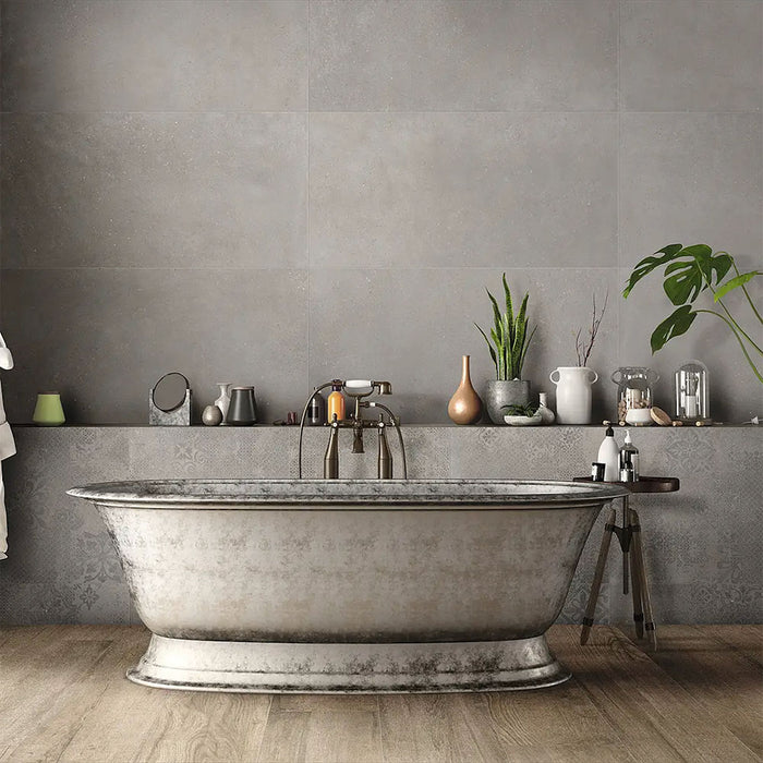 Bathroom interior featuring Tane Stone Grey Matt 30 × 60cm porcelain wall tiles, styled with a freestanding bath, vintage-style fittings, greenery, and warm wood flooring for a characterful, contemporary space.