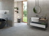 Bathroom interior featuring Tane Stone Grey Matt 60 × 60cm porcelain wall and floor tiles, styled with a freestanding bath, floating vanity, black fittings, and soft grey tones for a calm, contemporary finish.