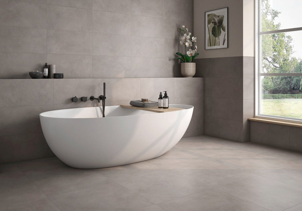 Bathroom interior featuring Tane Stone Grey Matt 60 × 60cm porcelain wall and floor tiles, styled with a freestanding bath, black fittings, soft neutral tones, and natural light for a calm, contemporary space.