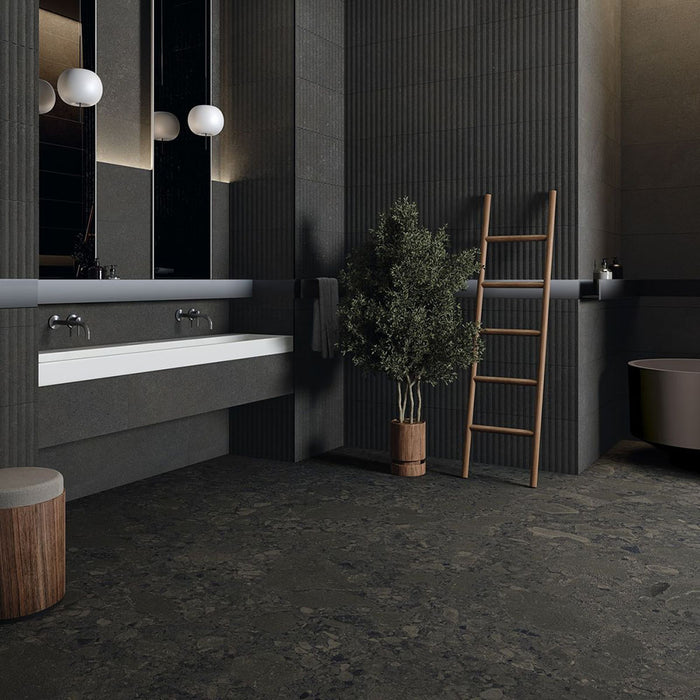 Modern bathroom featuring Terrace Terrazzo Black 60x60cm porcelain tiles on the floor and walls. The dark charcoal terrazzo effect creates a bold, contemporary look, paired with fluted wall panels, a floating white vanity, timber accents and soft globe lighting for a sophisticated, luxurious finish.