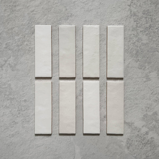 Zellij Chalk White Brick Moroccan-style tiles in a 6.5cm x 20cm brick format, featuring a soft matt white finish and subtle handmade surface variation, displayed as a flat lay on a neutral stone-effect background.