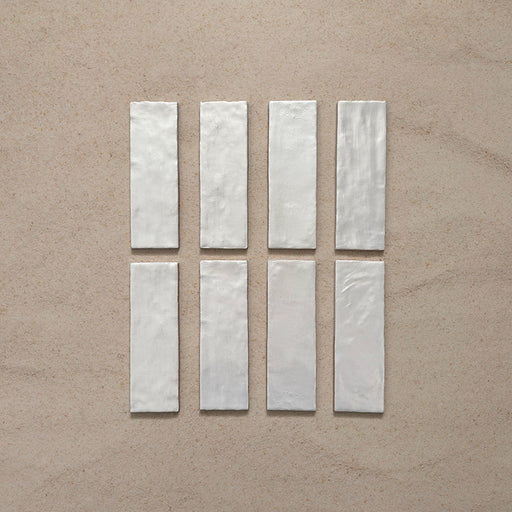 Zellij Oyster Brick Moroccan-style tiles in a 6.5cm x 20cm brick format, featuring a glossy off-white glaze with subtle surface variation, shown as a flat lay on a neutral background.