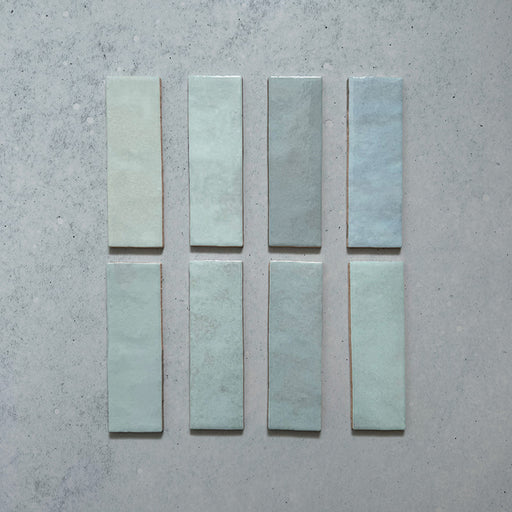 Zellij Aqua Blue brick tiles, 6.5cm x 20cm, Moroccan style, soft aqua blue colour with gentle tonal variation, glossy glazed finish, subtly uneven handcrafted surface, rectangular brick format shown as individual tiles on a neutral background.