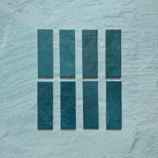 Zellij Peacock Green brick tiles, 6.5cm x 20cm, Moroccan style glazed ceramic wall tiles in rich peacock green tones with natural shade variation, glossy finish, and subtly uneven handcrafted texture, shown as individual tiles on a neutral textured background.