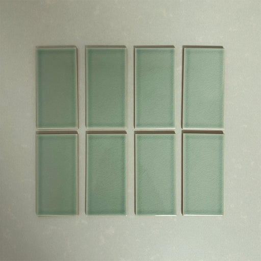 Flat lay of Finchley Lime Green 7.5 × 15cm ceramic tiles with a crackle glaze finish, highlighting soft green tones, subtle surface texture and gentle tonal variation for elegant wall tile designs.