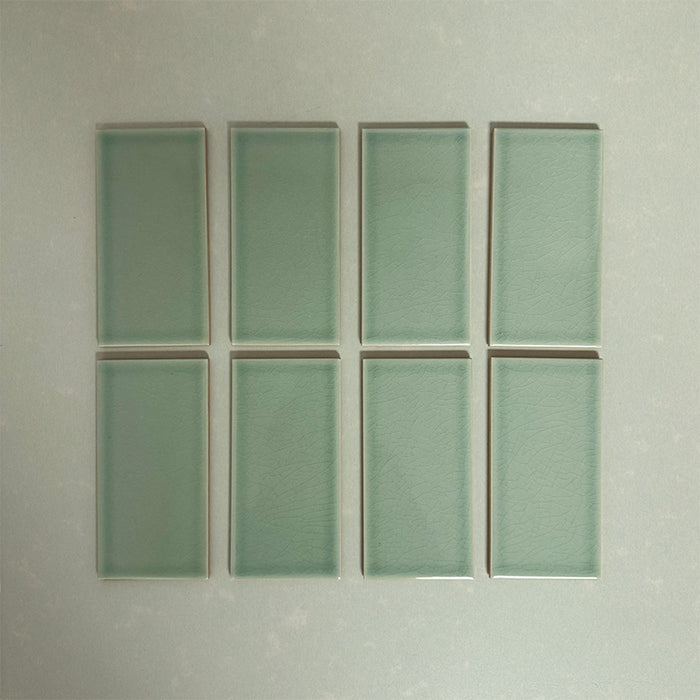 Flat lay of Finchley Lime Green 7.5 × 15cm ceramic tiles with a crackle glaze finish, highlighting soft green tones, subtle surface texture and gentle tonal variation for elegant wall tile designs.
