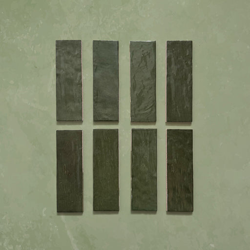 Zellij Botanical Green brick tiles, 6.5cm x 20cm, Moroccan style glazed ceramic tiles in deep botanical green shades with natural colour variation, glossy finish, and softly uneven handcrafted surface texture, shown as individual tiles on a neutral background.