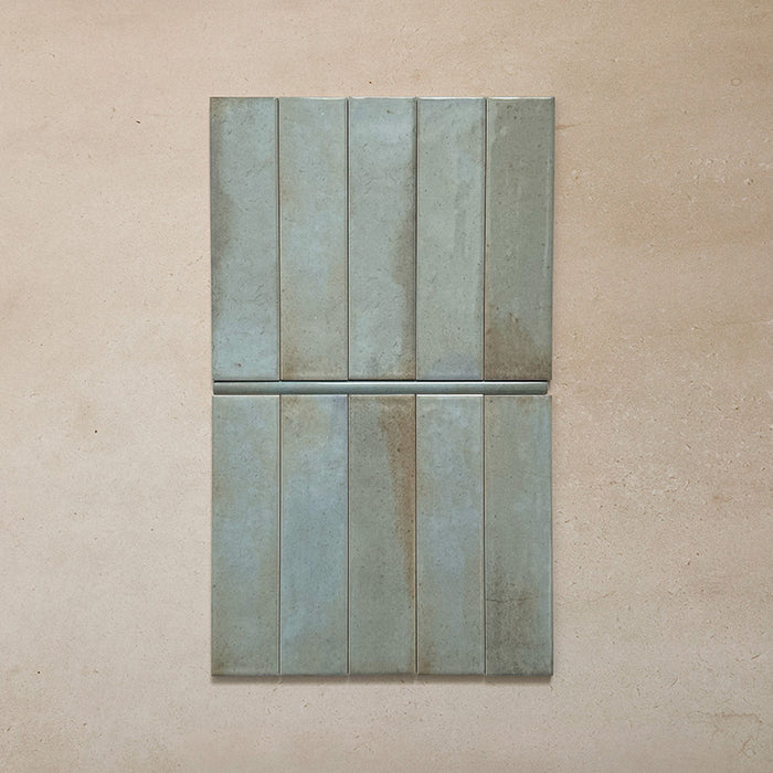 Izmir Celadon Green Gloss Pencil Bullnose Border Tile 1.2x30cm shown with matching 6x25cm brick tiles on a neutral beige background, highlighting the curved border edge and glossy handcrafted finish.