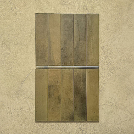 Izmir Daisy Green Gloss Pencil Bullnose Border Tile 1.2x30cm shown with matching 6x25cm brick tiles on a textured beige background, highlighting the glossy green glaze and smooth rounded border edge.