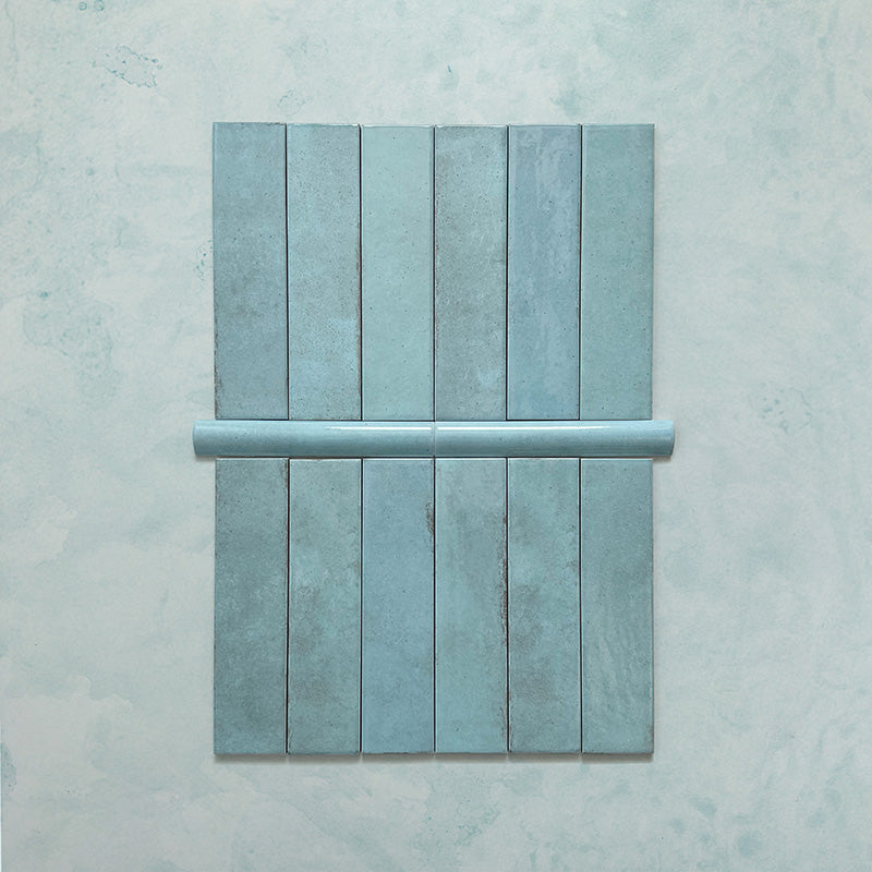 Madison Aquamarine Bullnose Pencil Border Tiles 3x20cm — shown with matching brick tiles, this elegant border piece completes the look with a soft, curved edge. The glossy teal glaze adds a polished finish, ideal for framing tiled walls or creating refined transitions in kitchens and bathrooms.