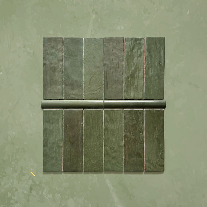 Zellij Botanical Green brick tiles with matching bullnose, 6.5cm x 20cm, Moroccan brick format in deep botanical green tones with natural tonal variation, glossy glazed finish, and softly uneven handcrafted surface, shown in a grouped tile and trim layout.