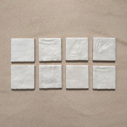 Zellij Oyster Square Moroccan-style tiles in a 10cm x 10cm format, featuring a glossy off-white glaze and subtle handmade surface variation, displayed as a flat lay on a neutral background.