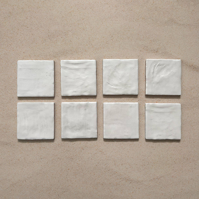 Zellij Oyster Square Moroccan-style tiles in a 10cm x 10cm format, featuring a glossy off-white glaze and subtle handmade surface variation, displayed as a flat lay on a neutral background.
