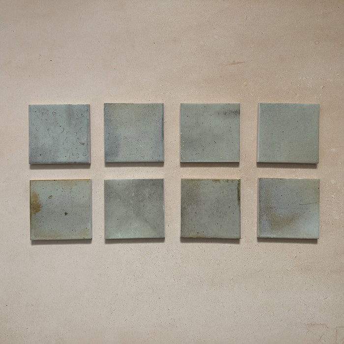 Beijing Celadon Green Square 10x10cm Moroccan-style ceramic wall tiles, styled on a neutral beige background to highlight their soft glaze and handcrafted variation.