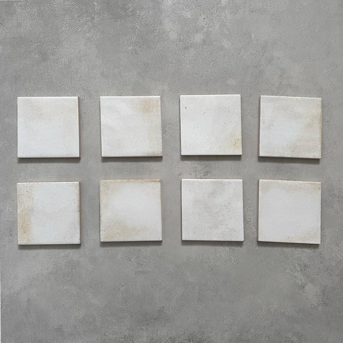 Beijing White 10x10cm Moroccan square tiles displayed on a grey surface, showing natural shade variation, uneven edges, and a handcrafted glazed finish for an authentic artisanal look.