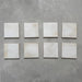 Beijing White 10x10cm Moroccan square tiles displayed on a grey surface, showing natural shade variation, uneven edges, and a handcrafted glazed finish for an authentic artisanal look.