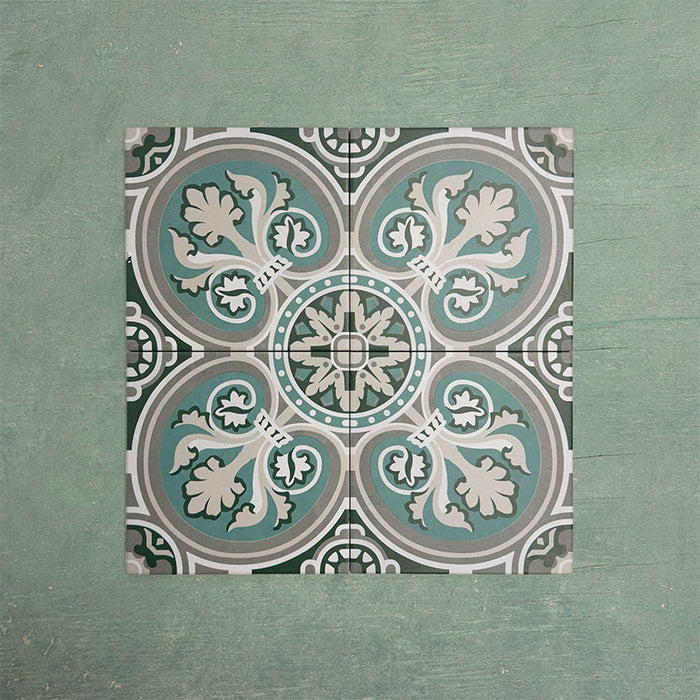 Four Europa Toulouse 20x20cm Victorian Moroccan style tiles displayed together against a textured green background, forming a symmetrical decorative pattern in green, grey and cream tones in a styled product setting.