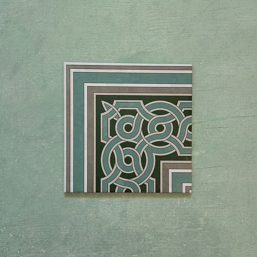 Single Europa Toulouse Corner 20x20cm Victorian Moroccan style tile displayed against a textured green background, featuring a decorative corner border design in green, grey and cream tones.