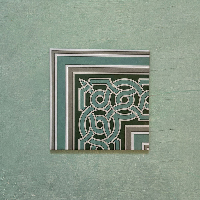 Single Europa Toulouse Corner 20x20cm Victorian Moroccan style tile displayed against a textured green background, featuring a decorative corner border design in green, grey and cream tones.