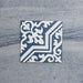 Single Europa Trondheim Blue 20x20cm Victorian Moroccan style tile displayed against a textured grey background, featuring a decorative geometric and floral pattern in blue and white tones in a close-up product setting.
