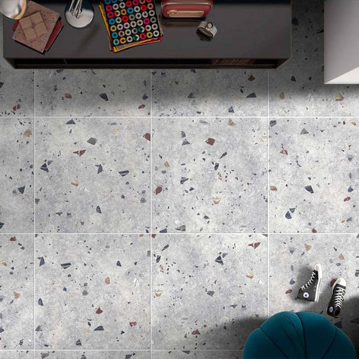 Top-down interior view featuring Tulsa Silver Terrazzo 66 × 66cm porcelain wall and floor tiles, showcasing a soft grey base scattered with multicoloured aggregate chips, styled with modern furnishings for a clean, contemporary finish.