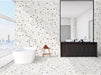 Bathroom interior featuring Tulsa White Terrazzo Hexagon 25 × 22cm porcelain wall and floor tiles, with a crisp white base and multicoloured aggregate chips, laid in a continuous honeycomb pattern and paired with a freestanding bath and dark wood vanity for a clean, contemporary contrast.