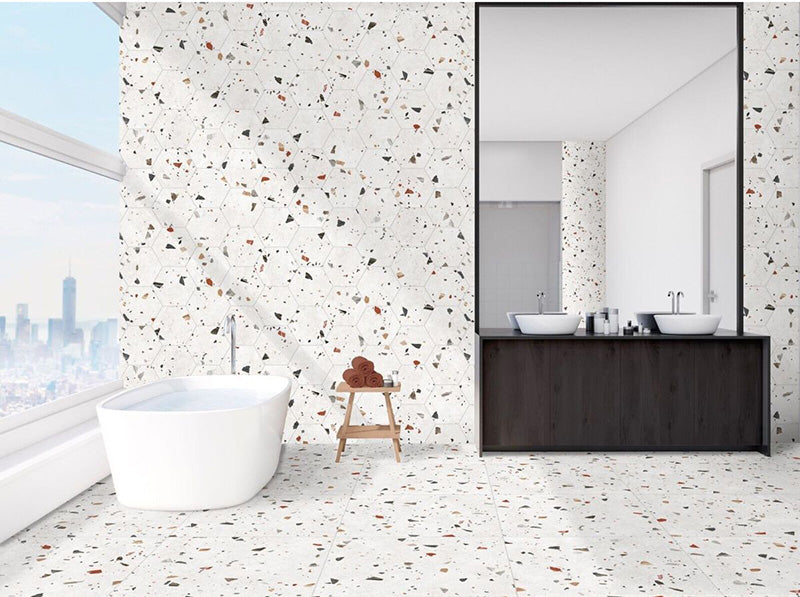 Bathroom interior featuring Tulsa White Terrazzo Hexagon 25 × 22cm porcelain wall and floor tiles, with a crisp white base and multicoloured aggregate chips, laid in a continuous honeycomb pattern and paired with a freestanding bath and dark wood vanity for a clean, contemporary contrast.