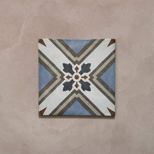 Single tile from the Carnaby Turner Victorian-style collection, 20x20cm porcelain wall and floor tile, featuring a blue, cream, and charcoal geometric cross pattern with small gold accents on an aged background.